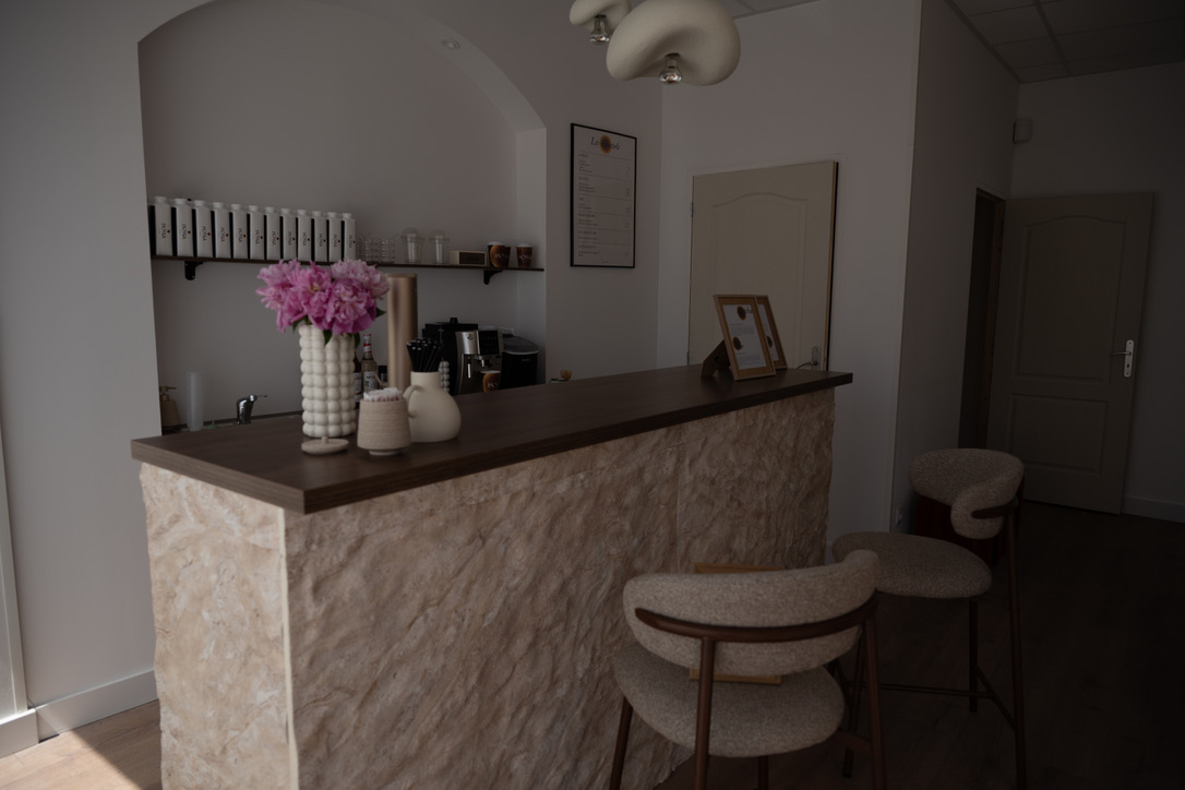 Comptoir d'accueil en pierre du studio LOUMA Pilates avec deux tabourets bouclé crème et bouquet de pivoines
