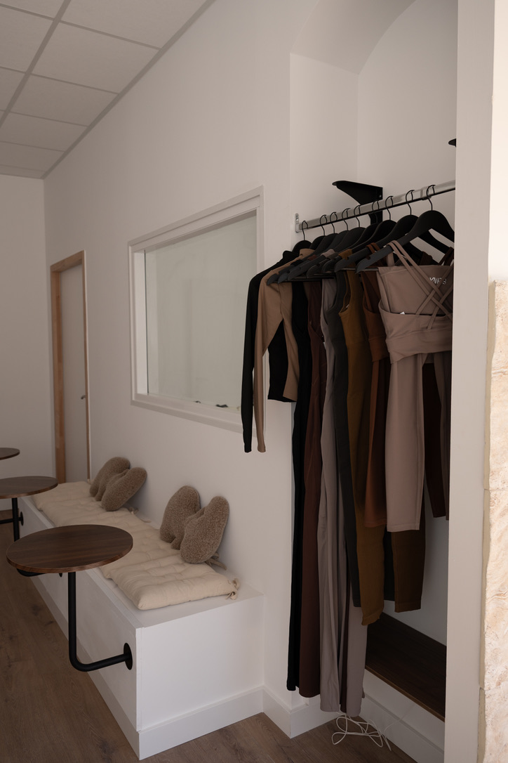 Vestiaire du studio LOUMA Pilates : portant de tenues, banquette et chaussons